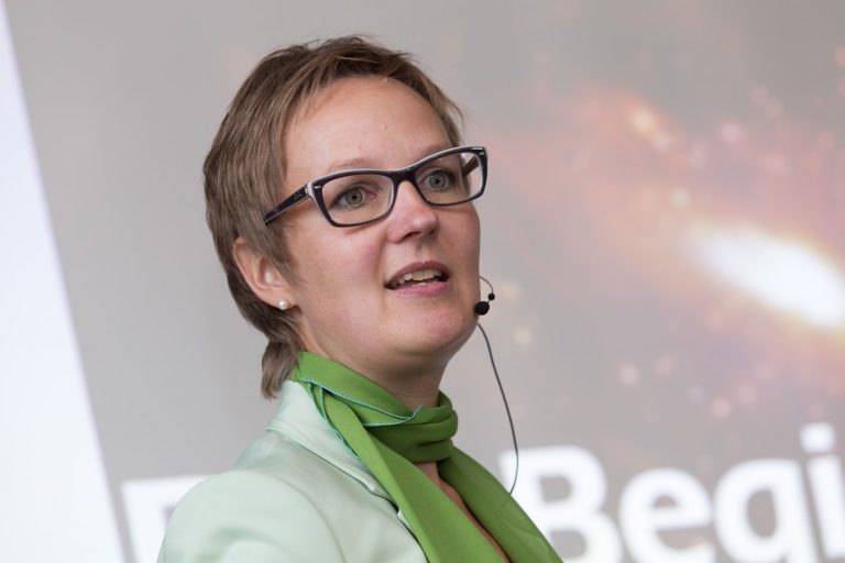 Sandra Kroning Portrait Rednerin mit Headset-Micro vor Leinwandausschnitt