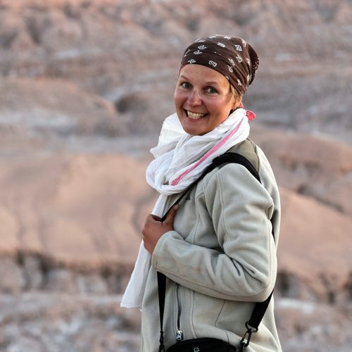 Halbportrait Sandra Kroning vor unscharfer rötlicher Felsenlandschaft